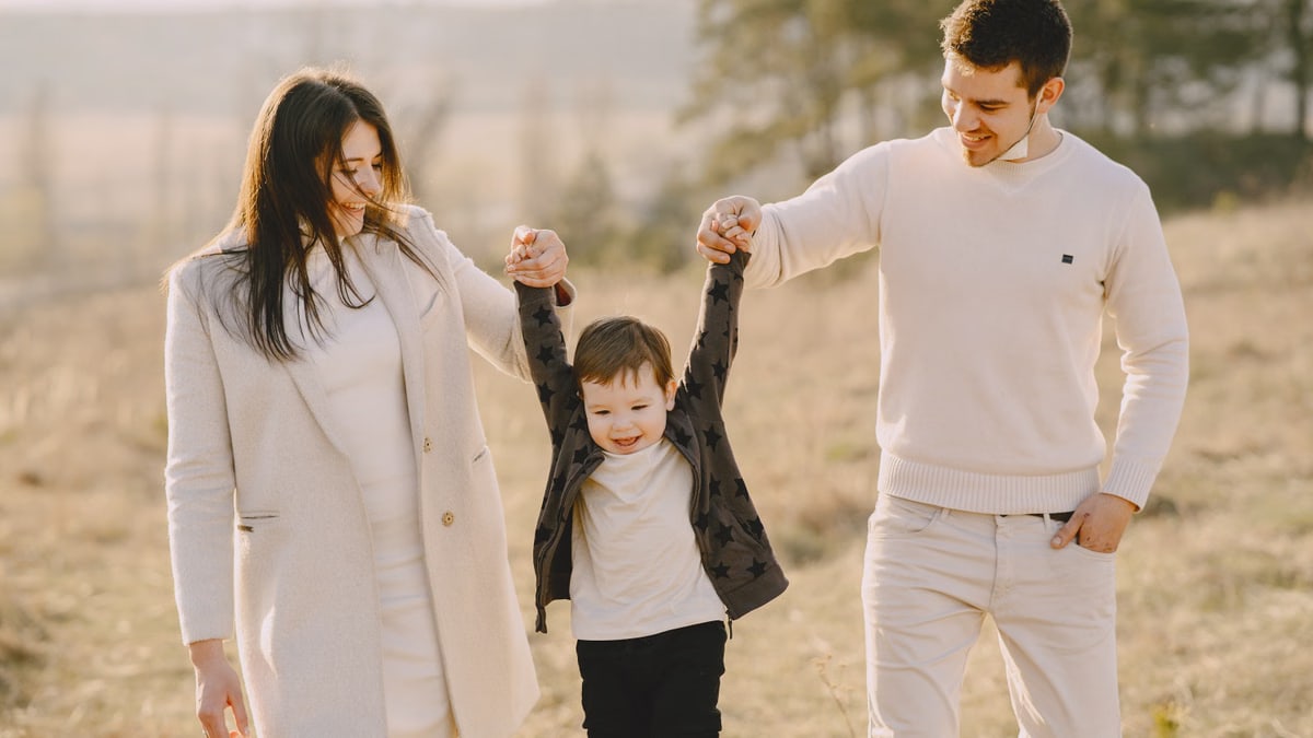 A joyful family of three enjoying a sunny day outdoors in nature.